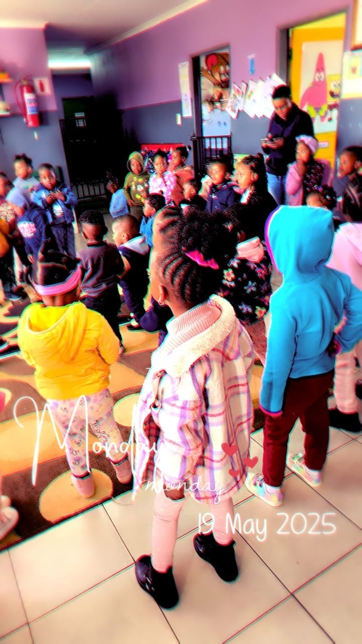 Children gathered in a vibrant purple and yellow indoor play area, dated May 19, 2025, during a group activity or party event
