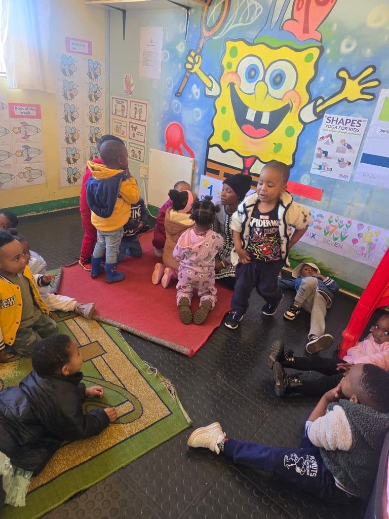 Young children gathered in a colorful classroom with SpongeBob murals and educational posters on the walls during activity time