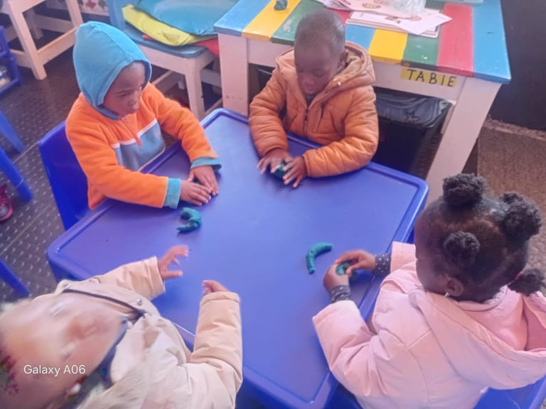 Children sitting at a blue table during an educational activity or lesson in a classroom setting