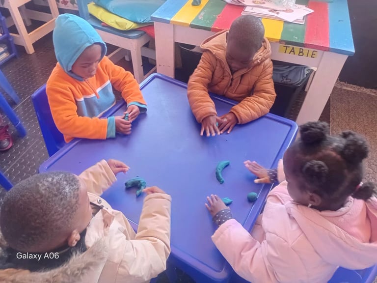 Children gathered around a blue table engaged in a hands-on activity in a classroom or learning center