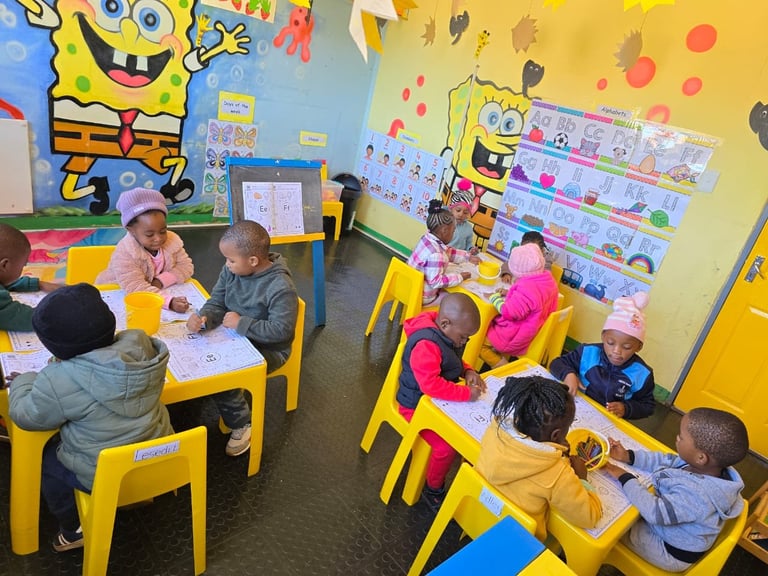Children sitting at yellow tables in a SpongeBob-themed classroom with bright yellow and blue walls decorated with character cutouts