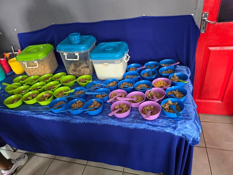 Table display of meal prep containers with colorful bowls and storage containers arranged on a blue tablecloth
