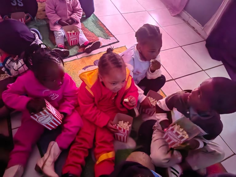 Group of children sitting on floor eating popcorn at an indoor event or party